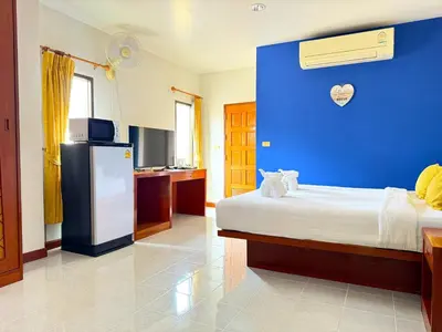 a bedroom with a blue wall with a bed and a refrigerator at Diamond Place Ao Nang in Ao Nang Beach