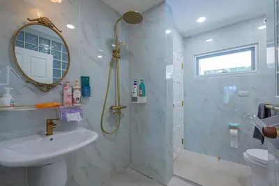 a bathroom with a sink and a shower with a mirror at Coco Golf Villa in Ban Huai Luk (1)