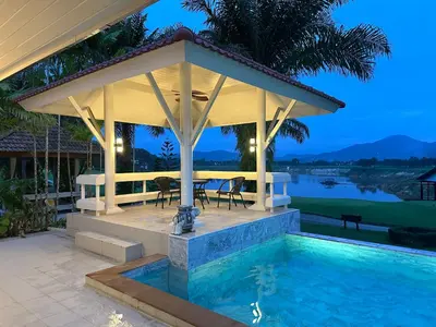 a pavilion with a table and chairs next to a pool at Coco Golf Villa in Ban Huai Luk (1)