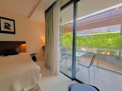 a bedroom with a bed and a balcony with a table and chairs at Studio Apartment 400m from Rawai Beach in Phuket Town