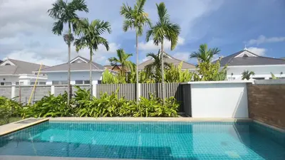 a swimming pool in front of a house with palm trees at Kamala Garden View Baan Ratri 4 in Kamala Beach