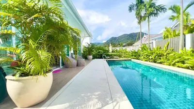 a swimming pool next to a house with palm trees at Kamala Garden View Baan Ratri 4 in Kamala Beach