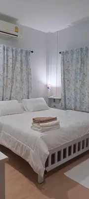 a bedroom with a bed with white sheets and curtains at B&N House in Nai Yang Beach