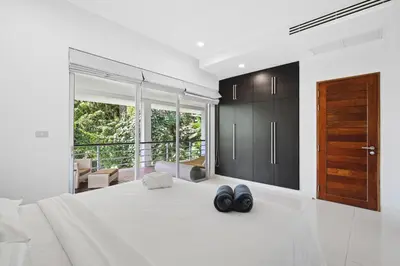 a bedroom with a large bed with two black shoes on it at Kamala Hills Naka - Villa 15 in Kamala Beach