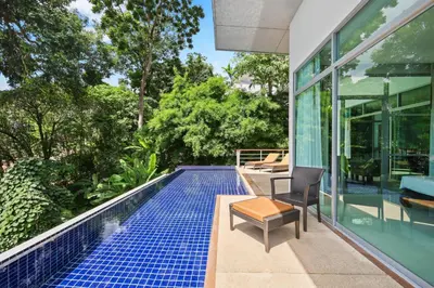 a swimming pool next to a house with a table and a chair at Kamala Hills Naka - Villa 15 in Kamala Beach