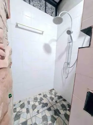 a bathroom with a shower with a tiled floor at บ้านพัก น้ำตกกะทู้ in Ban Huai Luk (1)