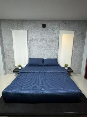 a large blue bed in a bedroom with two windows at Mimi Home in Ko Yao Noi