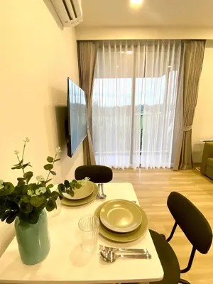 a living room with a table with plates and a tv at Cozy 1BR in Laguna Skypark Celeste Bangtao, Iinfinity Pool in Bang Tao Beach