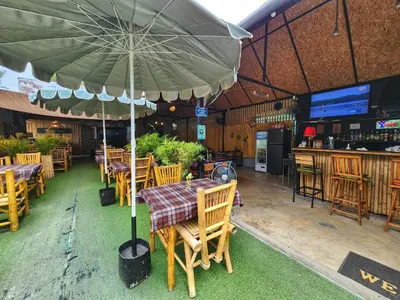 a restaurant with tables and chairs with an umbrella at Bambus Restaurant, Bar & Hostel in Patong Beach