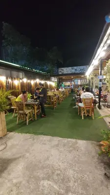 a group of people sitting at tables at a restaurant at night at Bambus Restaurant, Bar & Hostel in Patong Beach