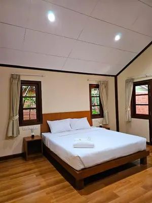 a bedroom with a large white bed with two windows at Samran Resort in Chalong