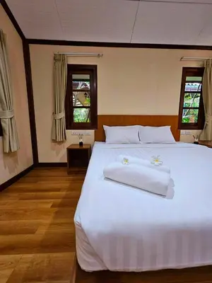 a bedroom with a large white bed with towels on it at Samran Resort in Chalong