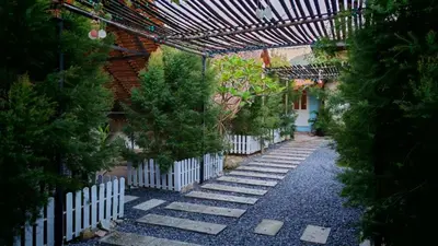 a garden with a white fence and trees at Bambus Restaurant, Bar & Glamping in Patong Beach