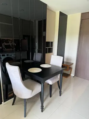 a black dining room table with white chairs in a kitchen at Mida Grande Resort Surin by Mill in Surin Beach
