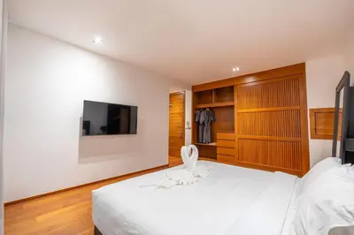 a bedroom with a white bed and a tv at Eva Beach Villa\u62c9\u5a01\u4e09\u5367\u5168\u6d77\u666f\u522b\u5885 in Ban Saiyuan (1)