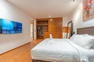 a bedroom with a large white bed with a television on the wall at Eva Beach Villa\u62c9\u5a01\u4e09\u5367\u5168\u6d77\u666f\u522b\u5885 in Ban Saiyuan (1)