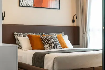 a bed with orange and white pillows in a bedroom at Title V Summer Dream Pool View Gym Hammam in Rawai Beach