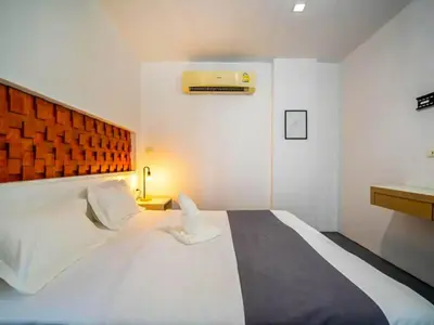 a bedroom with a large white bed and a desk at The Thai Guesthouse and Hostel in Patong Beach