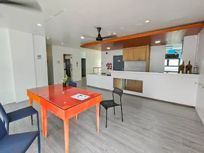 a living room with a table and chairs and a kitchen at The Thai Guesthouse and Hostel in Patong Beach