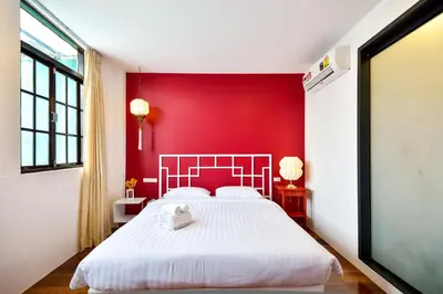 a bedroom with a red wall and a white bed at The Rommanee Classic Guesthouse in Phuket Town