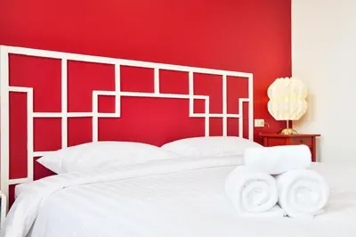 a bedroom with a white bed with a red wall at The Rommanee Classic Guesthouse in Phuket Town