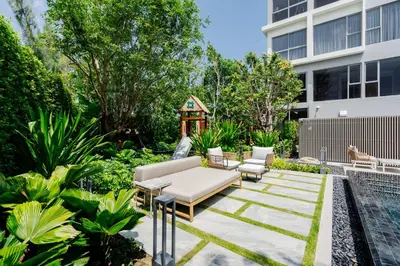 a garden with a couch and chairs in front of a building at Laguna Lakeside apartments with panoramic view in Bang Tao Beach