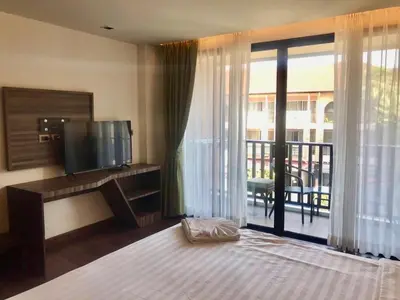 a bedroom with a bed and a television and a balcony at Kata Beach Guesthouse-The Beach Condo in Kata Beach