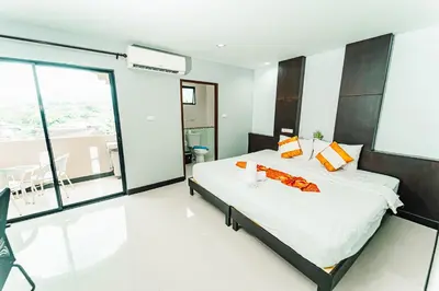 a bedroom with a large bed and a large window at Saiyuan Residence Phuket in Rawai Beach