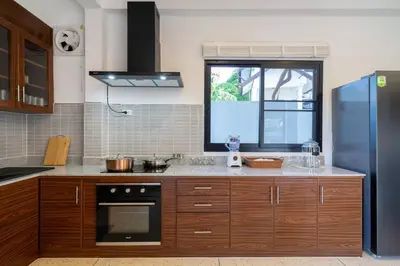 a kitchen with wooden cabinets and a blue refrigerator at Golden Sands Villa only 15 minutes walk to beach in Surin Beach