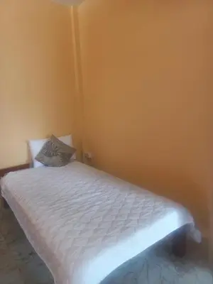 a bed in a room with a yellow wall at Salika Hostel Patong Phuket in Patong Beach
