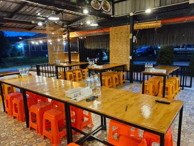 a restaurant with wooden tables and orange chairs at Khumkatang Resort & Restaurant in Ban Bang Rong