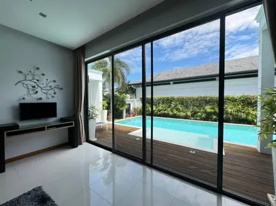 a living room with sliding glass doors and a swimming pool at Aromdee 2 Villa by G Estate Phuket in Ban Saiyuan (1)
