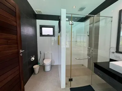 a bathroom with a glass shower and a toilet at Aromdee 2 Villa by G Estate Phuket in Ban Saiyuan (1)
