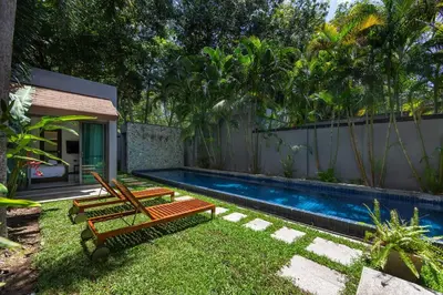 a backyard with a swimming pool and two wooden benches at Villa Laut 3BR Private Pool 10 min to Nai Harn in Rawai Beach