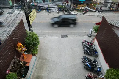 a car driving down a street next to parked motorcycles at Paripas Express Patong in Patong Beach
