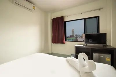 a bedroom with a bed and a tv and a window at Paripas Express Patong in Patong Beach