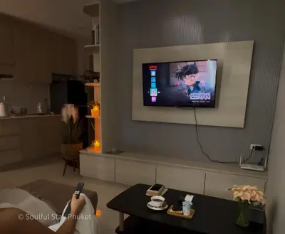 a person is sitting in a living room watching a tv at Soulful Stay Phuket -Distant Seaview and Mountain View Retreat, Patong in Patong Beach