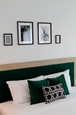 a bed with a green headboard with four pictures on the wall at Buasri Boutique Patong in Patong Beach