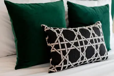 a black and white pillow on a bed with green pillows at Buasri Boutique Patong in Patong Beach