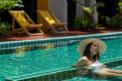 a woman in a hat sitting in a swimming pool at Buasri Boutique Patong in Patong Beach