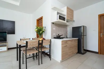 a kitchen with a table and chairs and a refrigerator at Apartment 1 Bedroom in Naiharn t in Ban Saiyuan (1)