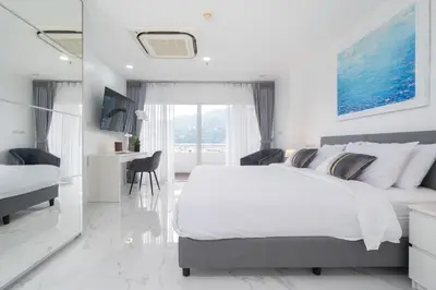 a white bedroom with a large bed and a desk at 1 Bedroom Brandnew Apartment in Patong Tower t in Patong Beach