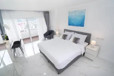 a white bedroom with a bed and a desk and chairs at 1 Bedroom Brandnew Apartment in Patong Tower t in Patong Beach