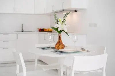 a white kitchen with a table with a vase with flowers at 1 Bedroom Brandnew Apartment in Patong Tower t in Patong Beach