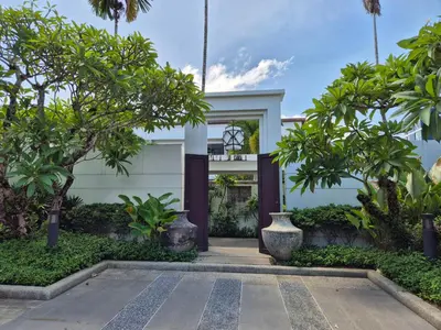 a white house with trees in front of it at Oxygen Condominium Bangtao in Ban Thalat Choeng Thale
