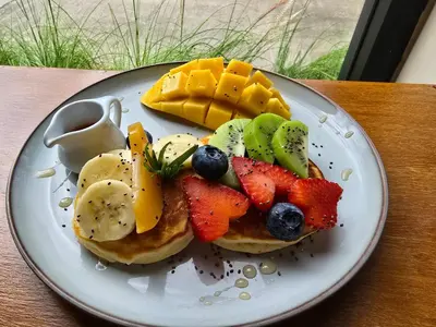 a plate of pancakes with fruit on a table at Oxygen Condominium Bangtao in Ban Thalat Choeng Thale