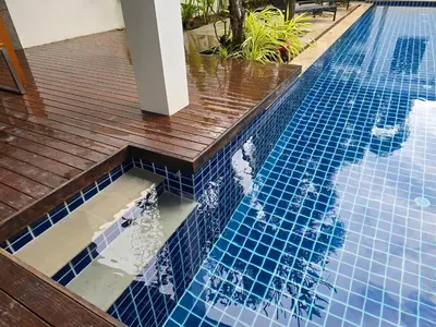a swimming pool with blue tiles and a wooden deck at Oxygen Condominium Bangtao in Ban Thalat Choeng Thale