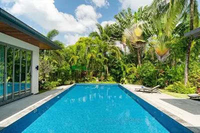a swimming pool in front of a house with palm trees at Baan Mandala Villa 4 in Bang Tao Beach