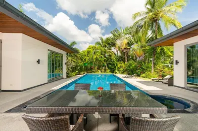 an outdoor dining area with a table and chairs next to a swimming pool at Baan Mandala Villa 4 in Bang Tao Beach