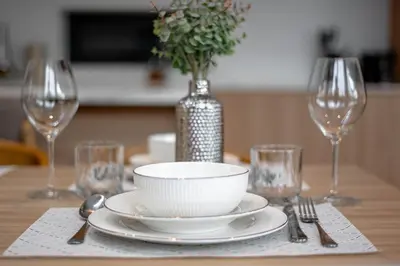 a table with a white bowl and plates and wine glasses at Grand Villa Aileen in Nai Yang Beach
